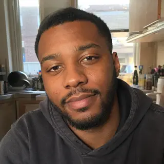 Natural customer-style portrait of a man wearing a charcoal hoodie at home