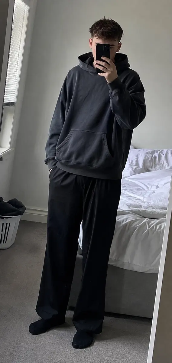 Phone-style mirror photo showing an oversized charcoal hoodie and loose black trousers