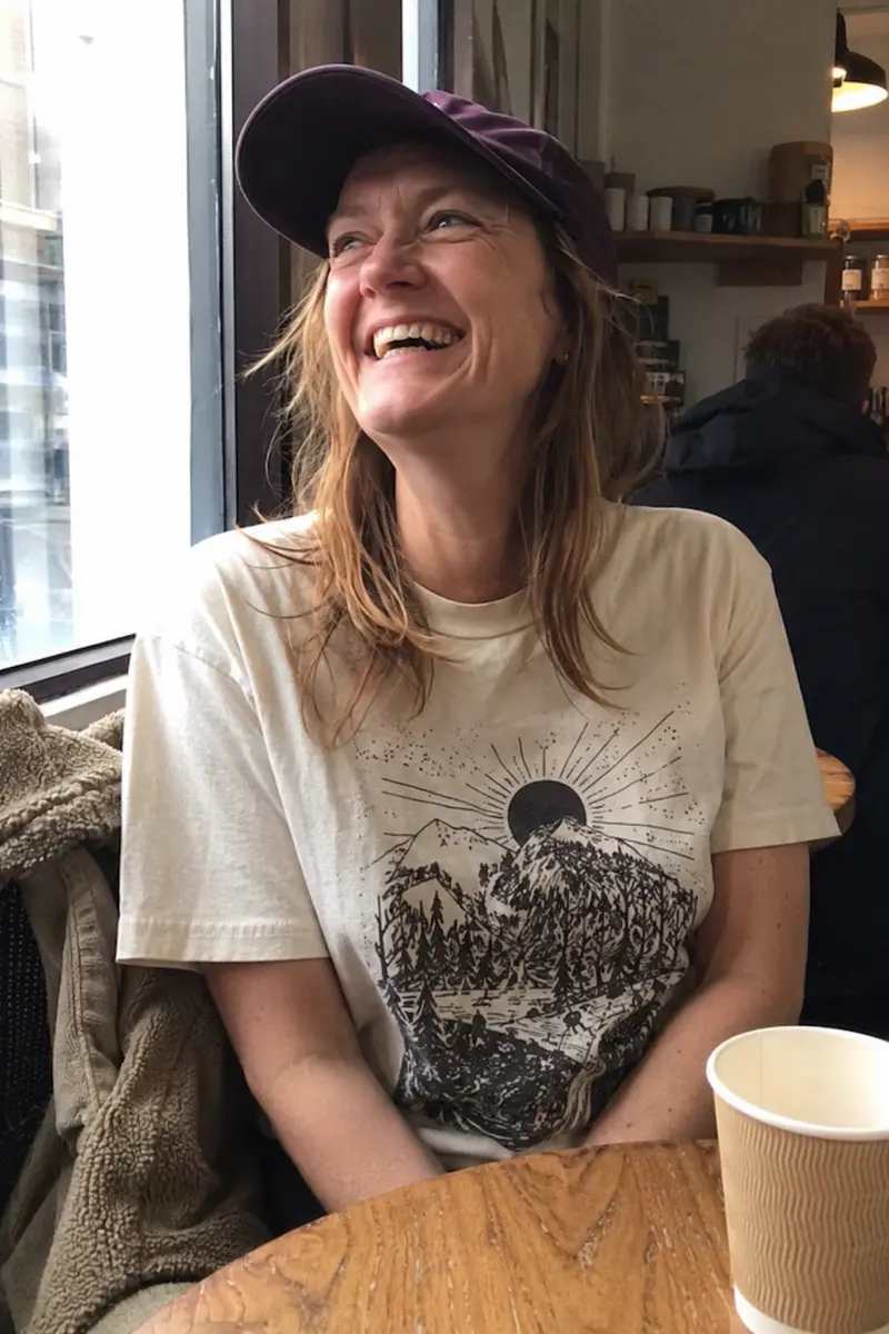 Phone-style cafe photo showing a cream graphic T-shirt and purple cap